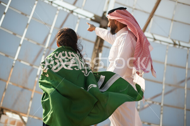 الاحتفال باليوم الوطني السعودي 92 ، صورة من الخلف لفتاة تضع علم المملكة العربية السعودية على ظهرها ،مستقبل السعودية، يوم العلم  ، محطات توليد الكهرباء عبر الطاقة الشمسية،ستلايت وألواح الطاقة الطبيعية المتجدده ، رؤية ومشاريع مستقبلية جديدة .