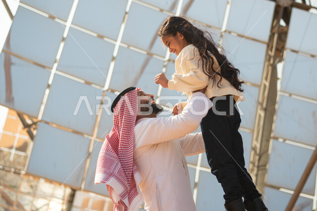 رجل عربي خليجي سعودي يلعب مع ابنته، رؤية السعودية 2030، توليد الكهرباء عبر الواح الطاقة الشمسية، الطاقة المتجددة، ستلايت والواح الطاقة الطبيعية المتجددة ، المشاريع السعودية المستقبلية، مستقبل الطاقة