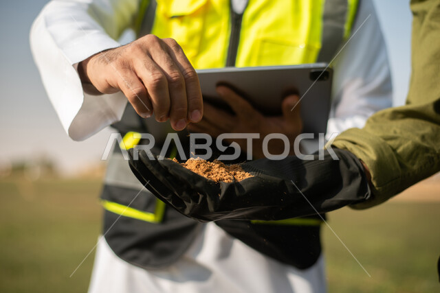تنميه المزارع والحقول الخضراء, صورة مقربة لمهندسان زراعيان عربيان خليجيان سعوديان يقومان بفحص التربة  ،  استخدام التقنية والتكنولوجيا لتطوير مستقبل القطاع الزراعي , تحسين انتاج المحاصيل الزراعية في السعودية  . 