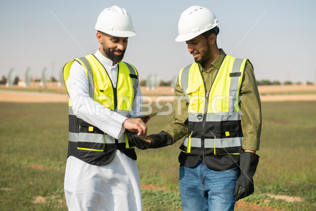 تحسين انتاج المحاصيل الزراعية في السعودية , صورة مقربة لمهندسان زراعيان عربيان خليجيان سعوديان يقومان بفحص التربة  ،  استخدام التقنية والتكنولوجيا لتطوير مستقبل القطاع الزراعي ,  تنميه المزارع والحقول الخضراء . 
