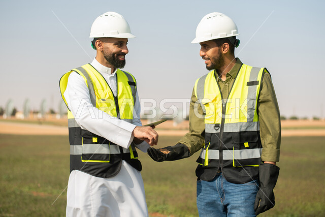 استخدام التقنية والتكنولوجيا لتطوير مستقبل القطاع الزراعي ,صورة مقربة لمهندسان زراعيان عربيان خليجيان سعوديان يقومان بفحص التربة  ،   تحسين انتاج المحاصيل الزراعية في السعودية , تنميه المزارع والحقول الخضراء . 