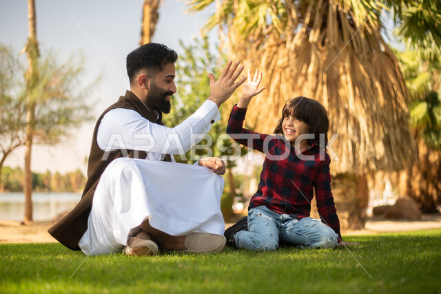 طفل ووالده عربيان خليجيان سعوديان , الاستمتاع باللعب , قضاء أوقات ممتعة في احد الحدائق العامة في المملكة العربية السعودية، أماكن سياحية ترفيهية بالسعودية، فعاليات ترفيهية عائلية