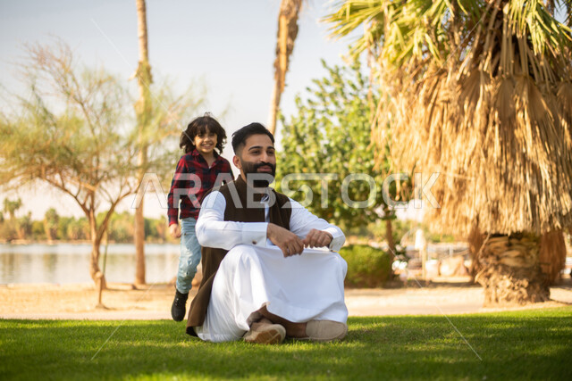 طفل ووالده عربيان خليجيان سعوديان , الاستمتاع باللعب , قضاء أوقات ممتعة في احد الحدائق العامة في المملكة العربية السعودية، أماكن سياحية ترفيهية بالسعودية، فعاليات ترفيهية عائلية