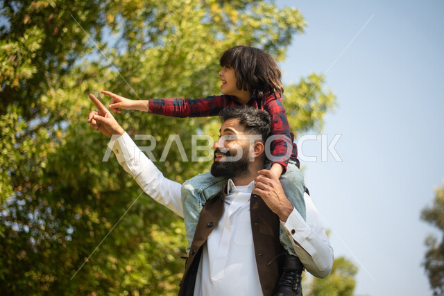 A young Saudi Arabian Gulf man and boy in a park, spending fun times in a park in Saudi Arabia, colorful balloons, summer vacation, a picnic in public parks, enjoying the outdoors, a green nature tour, a farm and restrooms, family entertainment activities