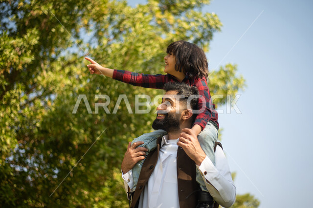 اب يحمل ابنه على ظهره ، قضاء وقت ممتع مع الابناء في احدى الحدائق, الاشارة الى شيء ما, عطلة صيفية، نزهه في الحدائق العامة، الاستمتاع في الهواء الطلق، جولة في الطبيعة الخضراء، مزرعة واستراحات، أنشطة ترفيهية عائلية