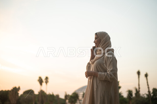 امرأة عربية خليجية سعودية  تجري مكالمة صوتية بإستخدام الهاتف المحمول ،  منتجع ترفيهي ،  حدائق ومنتزهات ترفيهية  ، الحدائق العامة في المملكة العربية السعودية.