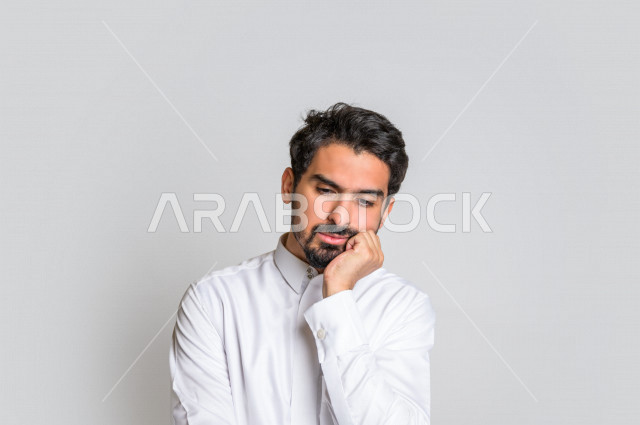 بورتريه لرجل عربي سعودي خليجي باللباس التقليدي , يقوم بإيماءات وجه ويدين تدل على التفكير و التركيز ، اشارات يدين تدل على الحيرة , خلفية بيضاء .