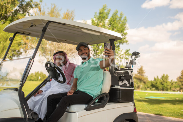 نادي الجولف ,رجلان عربيان خليجيان سعوديان داخل سيارة كهربائية لنقل الركاب، التقاط الصور بالهاتف المحمول ، أنشطة رياضية بالسعودية، رياضات الألعاب الأولمبية الصيفية، أنشطة ترفيهية ممتعة، ملعب الجولف، عربة الجولف