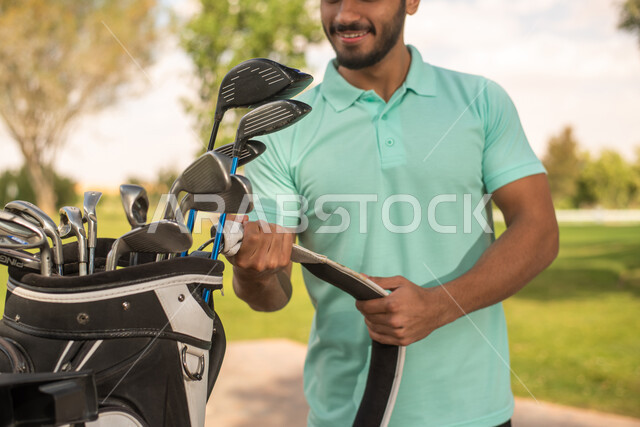 صورة مقربة لرجل عربي خليجي سعودي في ملعب الجولف، الإستعداد لممارسة لعبة الغولف، حقيبة الجولف، أنشطة رياضية في السعودية، رياضات الألعاب الأولمبية الصيفية، أنشطة ترفيهية ممتعة، ملعب الجولف