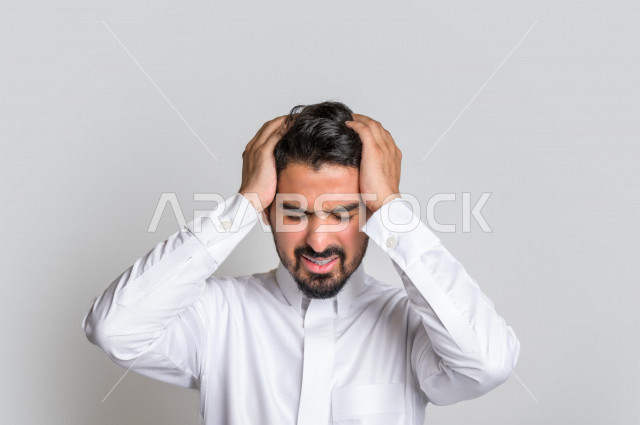 بورتريه لرجل عربي سعودي خليجي باللباس التقليدي , يقوم بإيماءات وجه ويدين تدل على الشعور بالصداع, ألم بالرأس, الإحساس بالمرض, التعب والإرهاق, الحاجه للعلاج, طلب المساعده , خلفية بيضاء .