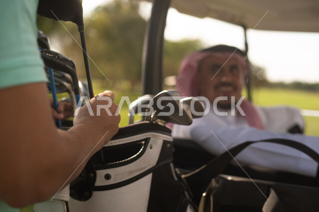 صورة مقربة لرجلان عربيان خليجيان سعوديان في ملعب الجولف، الإستعداد لممارسة لعبة الغولف، حقيبة الجولف، أنشطة رياضية بالسعودية، رياضات الألعاب الأولمبية الصيفية، أنشطة ترفيهية، ملعب الجولف