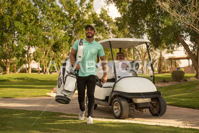 رجلان عربيان خليجيان سعوديان في ملعب الجولف، سيارة جولف كهربائية لنقل الركاب، ممارسة لعبة الغولف، مساحات واسعة خضراء، أنشطة رياضية، رياضة لعبة الجولف، الألعاب الأولمبية الصيفية، أنشطة ترفيهية ممتعة , خلفية الطبيعة الخضراء .