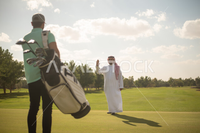 رجلان عربيان خليجيان سعوديان في ملعب الجولف، ايماءات تدل على  التحية والسلام, ممارسة لعبة الغولف على مساحات واسعة خضراء، أنشطة رياضية في السعودية، لعبة الجولف، رياضات الألعاب الأولمبية الصيفية، أنشطة ترفيهية، ملعب الجولف