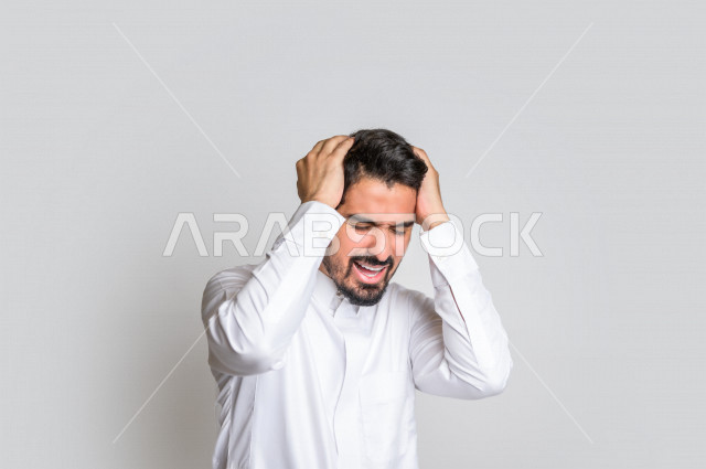 بورتريه لرجل عربي سعودي خليجي باللباس التقليدي , يقوم بإيماءات وجه ويدين تدل على الشعور بالصداع, ألم بالرأس, الإحساس بالمرض, التعب والإرهاق, الحاجه للعلاج, طلب المساعده , خلفية بيضاء .