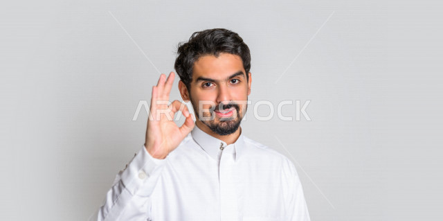 بورتريه لرجل عربي سعودي خليجي  باللباس التقليدي , يقوم بإيماءات وجه تدل على الرضى ، إشارات يدين تدل على الموافقة والإعجاب ، علامة الجودة , الإمتياز والتميز , القبول والموافقة , خلفية بيضاء .
