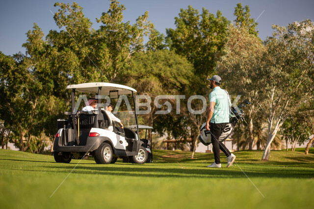 رجلان عربيان خليجيان سعوديان مع طفل صغير في ملعب الجولف، مساحات واسعة خضراء، سيارة كهربائية مختصة بنقل الركاب، ممارسة لعبة الغولف، أنشطة رياضية بالسعودية، لعبة الجولف، رياضات الألعاب الأولمبية الصيفية، أنشطة ترفيهية