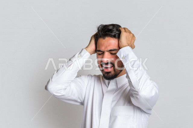 بورتريه لرجل عربي سعودي خليجي باللباس التقليدي , يقوم بإيماءات وجه ويدين تدل على الشعور بالصداع, ألم بالرأس, الإحساس بالمرض, التعب والإرهاق, الحاجه للعلاج, طلب المساعده , خلفية بيضاء .