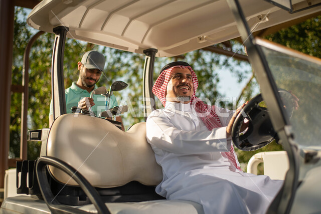 Playing golf on large green areas, two Saudi Arabian Gulf men on the golf course, an electric car for passenger transport, sports activities in Saudi Arabia, golf, Summer Olympics sports, recreational activities