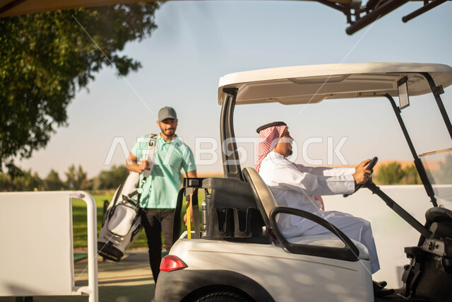 رجلان عربيان خليجيان سعوديان في ملعب الجولف، سيارة جولف كهربائية لنقل الركاب, ممارسة لعبة الغولف على مساحات واسعة خضراء، لعبة الجولف، رياضات الألعاب الأولمبية الصيفية، أنشطة رياضية  ترفيهية في السعودية, خلفية الطبيعة الخضراء.
