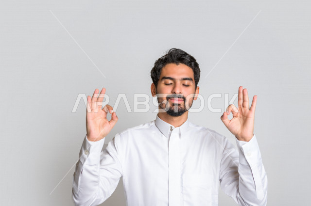 بورتريه لرجل عربي سعودي خليجي  باللباس التقليدي , يقوم بإيماءات وجه تدل على الرضى ، إشارات يدين تدل على الموافقة والإعجاب ، علامة الجودة , الإمتياز والتميز , القبول والموافقة , خلفية بيضاء .
