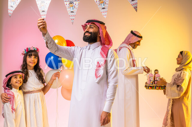 بورتريه لعائلة عربية خليجية سعودية تحتفل بقدوم العيد  ، الاحتفال بالعيد السعيد ، إيماءات وجه تدل على الفرح والسعادة ، أجواء العيد في السعودية ، بالونات وزينة العيد ، خلفية ملونة