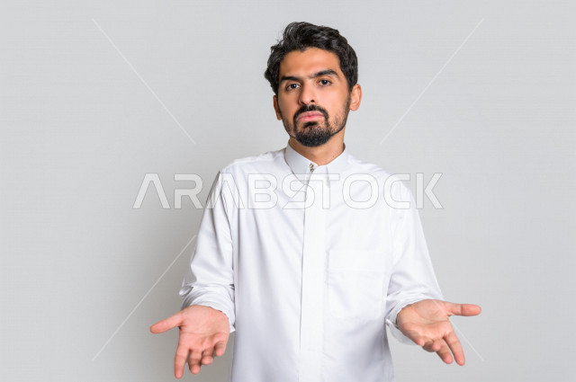 بورتريه لرجل عربي سعودي خليجي باللباس التقليدي , يقوم بإيماءات وجه ويدين تدل على التساؤل والإستغراب , الإستفهام عن شيء ما , عدم المعرفة ,خلفية بيضاء .