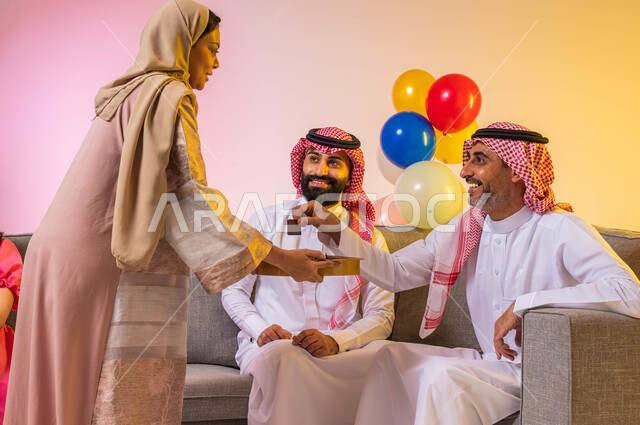 زيارات وتجمعات عائليه, اكرام الضيف وحسن الاستقبال ، بورتريه لعائلة عربية خليجية سعودية تحتفل بقدوم العيد وأمراه عربيه سعوديه خليجيه تقوم بتقديم حلوى العيد للضيوف, مناسبات واعياد اسلاميه ، خلفية ملونة