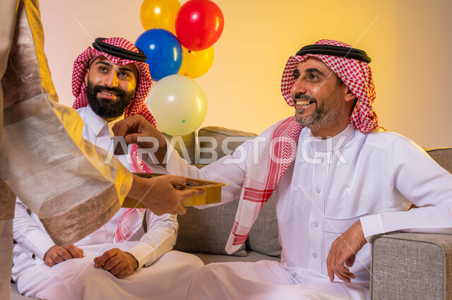بورتريه لعائلة عربية خليجية سعودية تحتفل بقدوم العيد وأمراه عربيه سعوديه خليجيه تقوم بتقديم حلوى العيد للضيوف, مناسبات واعياد اسلاميه, زيارات وتجمعات عائليه, اكرام الضيف وحسن الاستقبال ، خلفية ملونة