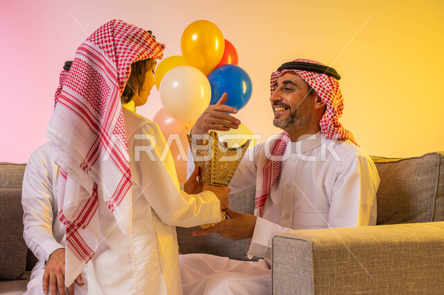 بورتريه لولد عربي سعودي خليجي يرتدي الزي السعودي التقليدي يحمل حامل البخور (المبخرة)  ، تبخير وتعطير وتطيب الضيوف , ايماءات تدل على الفرح والسعادة بالعيد السعيد ، احتفالات أعياد ومناسبات ، بالونات وزينة العيد ، خلفية ملونة