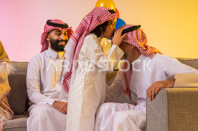 أجواء عائليه سعيده, بورتريه لعائلة عربية خليجية سعودية تحتفل بالعيد في غرفة الجلوس ، ولد عربي سعودي خليجي يقوم بتقبيل رأس جده, عيد مبارك, المناسبات والاعياد الاسلاميه ، بالونات وزينة العيد ، التهئنة بالعيد السعيد ، خلفية ملونة