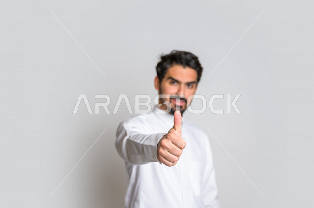 بورتريه لرجل عربي سعودي خليجي  باللباس التقليدي , يقوم بإيماءات وجه تدل على الرضى ، إشارات يدين تدل على الموافقة والإعجاب ، علامة الجودة , الإمتياز والتميز , القبول والموافقة , خلفية بيضاء .
