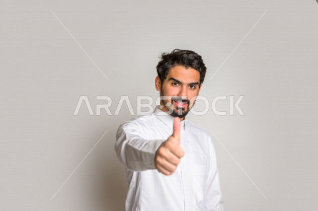 بورتريه لرجل عربي سعودي خليجي  باللباس التقليدي , يقوم بإيماءات وجه تدل على الرضى ، إشارات يدين تدل على الموافقة والإعجاب ، علامة الجودة , الإمتياز والتميز , القبول والموافقة , خلفية بيضاء .