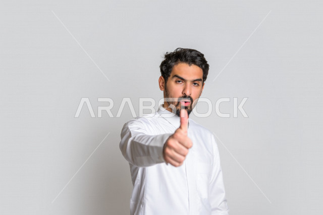بورتريه لرجل عربي سعودي خليجي  باللباس التقليدي , يقوم بإيماءات وجه تدل على الرضى ، إشارات يدين تدل على الموافقة والإعجاب ، علامة الجودة , الإمتياز والتميز , القبول والموافقة , خلفية بيضاء .