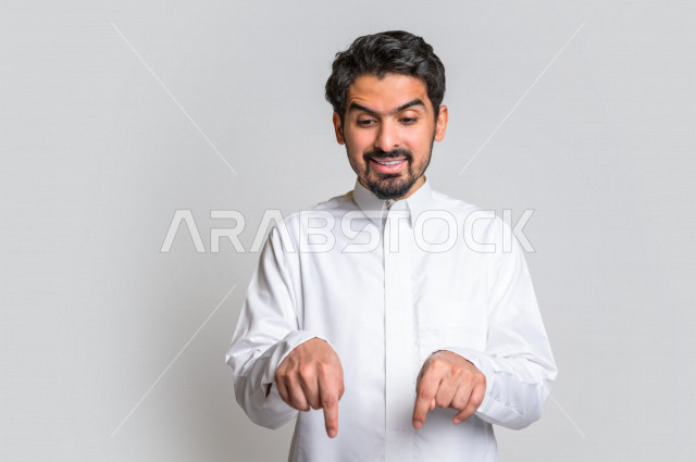 بورتريه لرجل عربي سعودي خليجي يرتدي الثوب السعودي, يؤشر بيديه للأسفل الى شيء ما , حركات تدل على المكان , خلفية بيضاء .