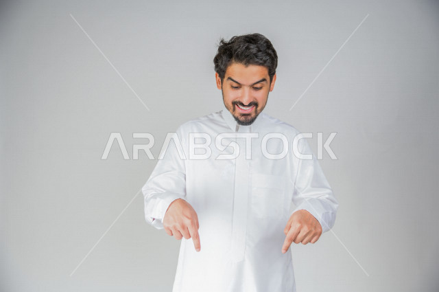 بورتريه لرجل عربي سعودي خليجي يرتدي الثوب السعودي, يؤشر بيديه للأسفل الى شيء ما , حركات تدل على المكان , خلفية بيضاء .