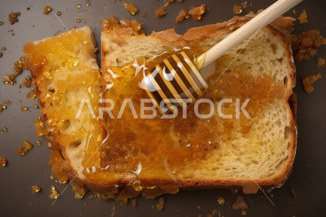 صورة من الأعلى لشريحة من التوست المحمص مدهون بالعسل , ملعقة العسل ,وجبة فطور صحية, فطور صحي ولذيذ, مأكولات ووجبات صحية .