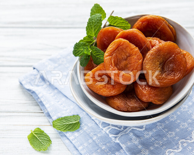 مشمش مجفف مع وعاء خزفي, نوع من أنواع الفواكه المجففة , المشمش المجفف , فواكه مجففة صحية ولذيذة , عنصر غذائي مفيد للصحة, خلفية بيضاء