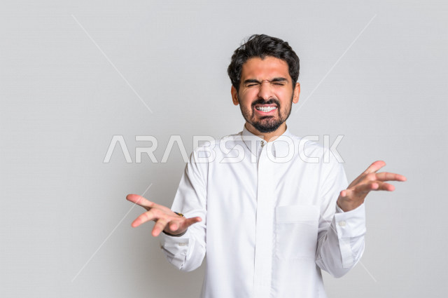 بورتريه لرجل عربي سعودي خليجي باللباس التقليدي , يقوم بإيماءات وجه ويدين تدل على الصراخ والتشاؤوم , التساؤل والإستغراب , الإستفهام عن شيء ما , خلفية بيضاء .