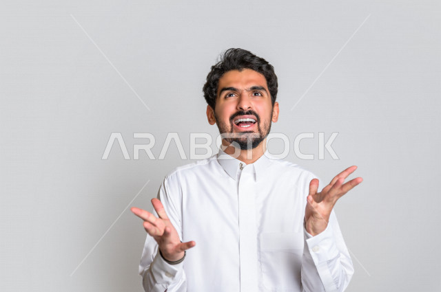 Portrait of a Saudi Arabian Gulf man in traditional dress, making facial and hands gestures indicating screaming and pessimism, questioning and amazement, white background.