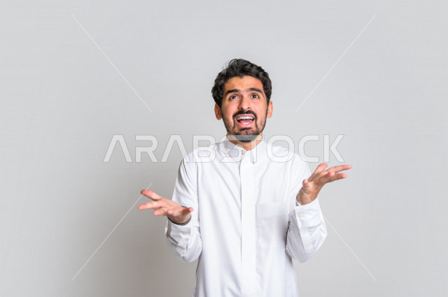 بورتريه لرجل عربي سعودي خليجي باللباس التقليدي , يقوم بإيماءات وجه ويدين تدل على الصراخ والتشاؤوم , التساؤل والإستغراب , الإستفهام عن شيء ما , خلفية بيضاء .