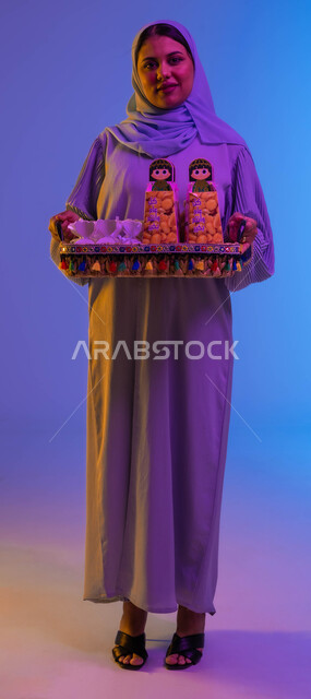 امرأة سعودية خليجية عربية تحمل ضيافة العيد، الضيافة السعودية، إكرام الضيف، حسن الضيافة والإستقبال، بهجه وفرحة العيد، عادات العيد في المجتمع السعودي، زيارات العيد، الاحتفال بالعيد السعيد، صورة الجسم بالطول الكامل، اعياد ومناسبات
