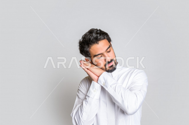 Portrait of a Saudi Arabian Gulf man wearing the Saudi dress, facial and hands gestures indicating sleepiness, feeling tired, needing sleep and rest, feeling tired, laziness and lethargy, sleeping deeply, white background.