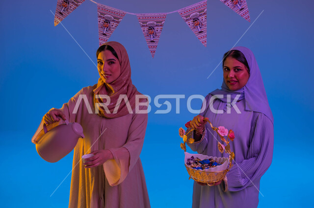 سيدتان عربيتان خليجيتان سعوديتان يحملن ضيافة العيد، الحلوى والقرقيعان، تقديم القهوة الساخنة، اجواء العائلة السعودية في العيد، حسن الضيافة والإستقبال، زيارات العيد، العيد بين الأهل، ايماءات وجه مبتسمة، الاحتفال بالعيد السعيد، أعياد ومناسبات، خلفية ملونة