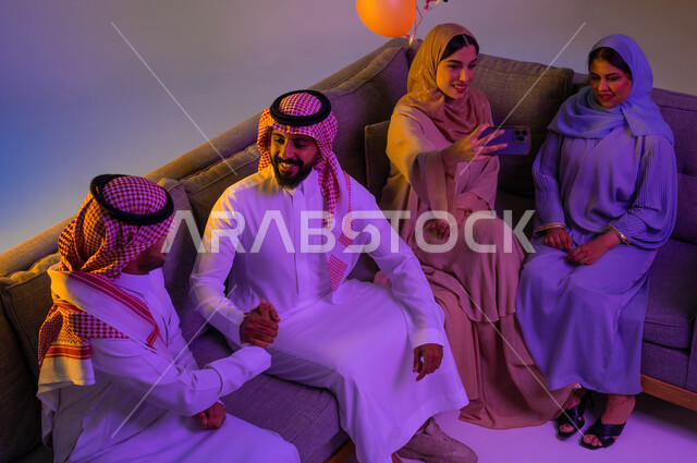 رجلان عربيان خليجيان سعوديان يتصافحان، اجواء العائلة السعودية في العيد، استخدام الهاتف المحمول، التقاط صور سيلفي تذكارية، الكاميرا الامامية، العيد بين الأهل، اللمة العائلية، عادات العيد في المجتمع السعودي، زيارات العيد، الاحتفال بالعيد السعيد