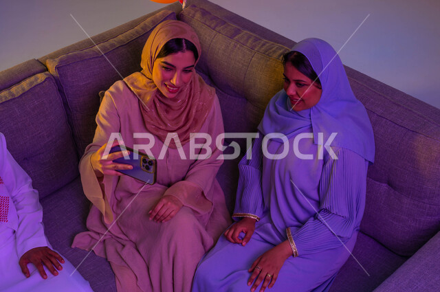 امرأتان عربيتان خليجيتان سعوديتان، استخدام الهاتف المحمول، اجواء العائلة السعودية في العيد، التقاط صور سيلفي تذكارية، الكاميرا الامامية، العيد بين الأهل، فرحة العيد، اللمة العائلية، عادات العيد في المجتمع السعودي، زيارات العيد، الاحتفال بالعيد السعيد