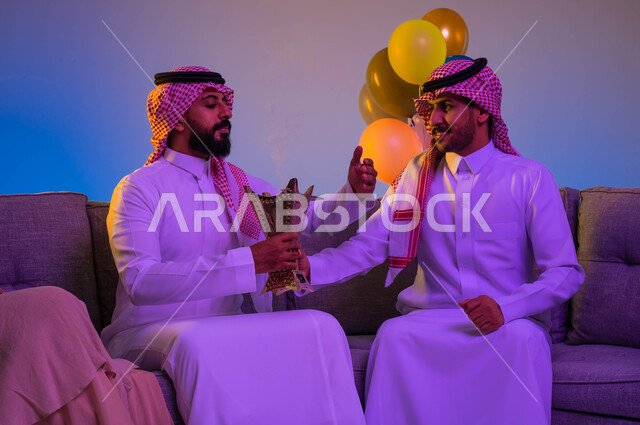 رجلان عربيان خليجيان سعوديان يحملان المبخرة، حامل البخور، استخدام خشب العود، المناسبات الاجتماعية والدينية، التطيب والتعطر، العيد في المجتمع السعودي، بهجة وفرحة العيد، الاحتفال بالعيد السعيد