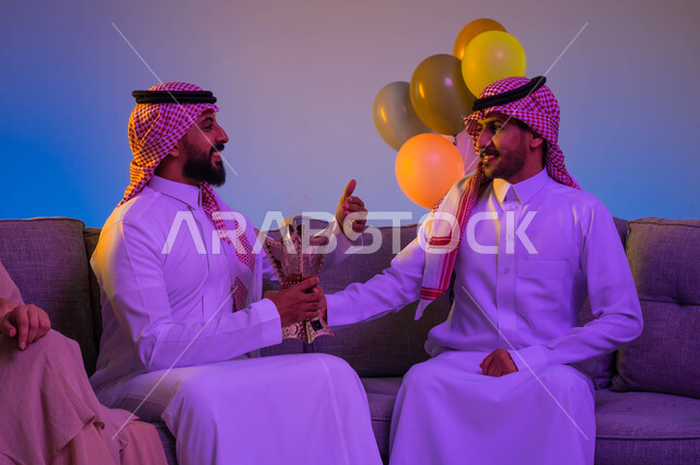 Two Saudi Arabian Gulf men carrying the incense burner, the use of oud wood, the incense holder, social and religious occasions, perfuming and perfuming, the feast in Saudi society, the joy and joy of the feast, the celebration of the happy feast