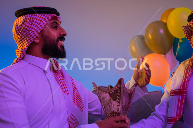 رجلان خليجيان سعوديان عربيان، يحملان حامل البخور، المبخرة، استخدام خشب العود، المناسبات الاجتماعية والدينية، التطيب والتعطر، العيد في المجتمع السعودي، بهجة وفرحة العيد، الاحتفال بالعيد السعيد