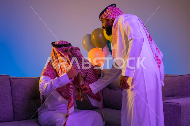 رجلان عربيان سعوديان خليجيان يستخدمان المبخرة، استخدام خشب العود في المناسبات الاجتماعية والدينية، حامل البخور، التطيب والتعطر، العيد في المجتمع السعودي، بهجة وفرحة العيد، الاحتفال بالعيد السعيد