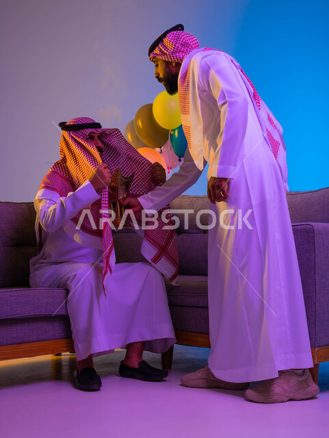 رجلان خليجيان عربيان سعوديان يستخدمان حامل البخور، المبخرة، استخدام خشب العود في المناسبات الاجتماعية والدينية، التطيب والتعطر، العيد في المجتمع السعودي، بهجة وفرحة العيد، الاحتفال بالعيد السعيد